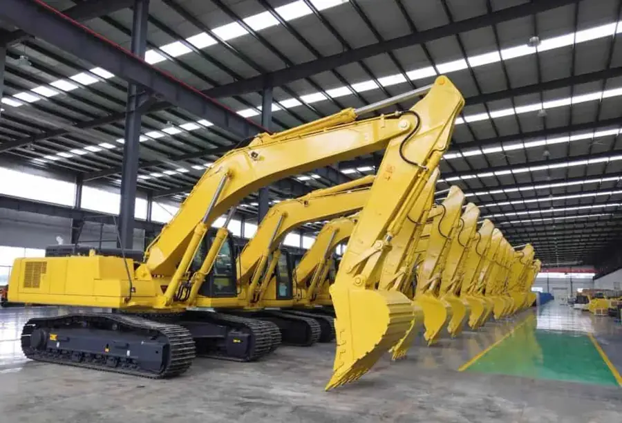 Construction machinery lined up in a factory warehouse